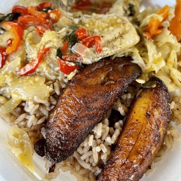Caribbean meal with stewed fish, red peppers, onions, rice, and two fried plantains.